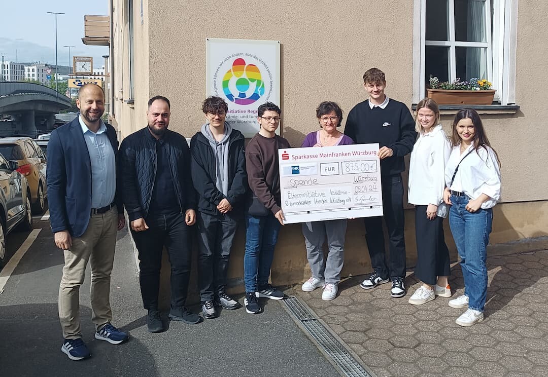Die IHK-Auszubildenden überreichen den Spendenscheck im Beisein von IHK-Hauptgeschäftsführer Dr. Sascha Genders (links) an die Würzburger Elterninitiative Regenbogen. Foto: Elterninitiative Regenbogen