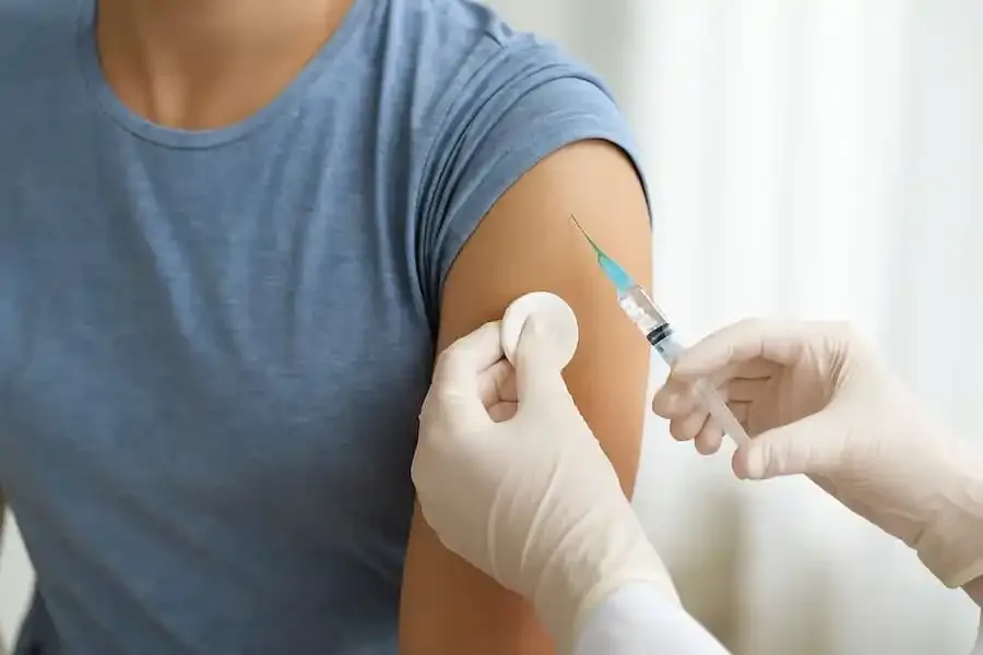 Ärztin verabreicht Impfung gegen Hepatitis B am Oberarm eines Patienten.