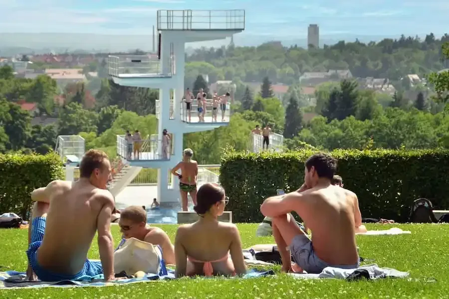 Badegäste im SILVANA Freibad Schweinfurt mit Blick auf den Sprungturm bei sommerlichem Wetter
