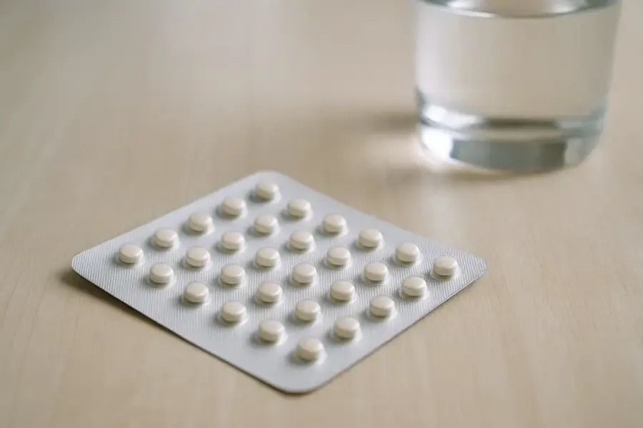 Blisterpack mit Antibabypille auf Holztisch neben Glas Wasser
