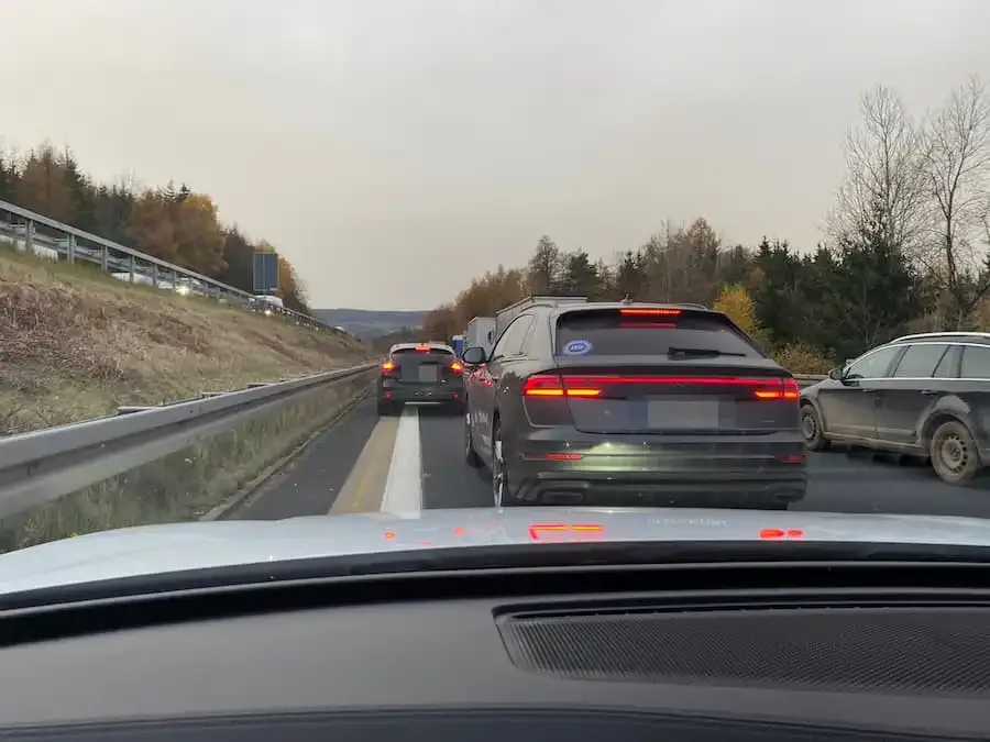Autos im Stau auf der Autobahn mit gebildeter Rettungsgasse, während ein Fahrzeug die Spur blockiert.
