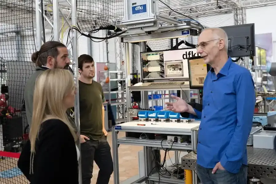 Tim Schwartz vom DFKI erklärt Mitarbeitenden der HWK Unterfranken die Funktionsweise einer Tracking-KI im Forschungslabor.