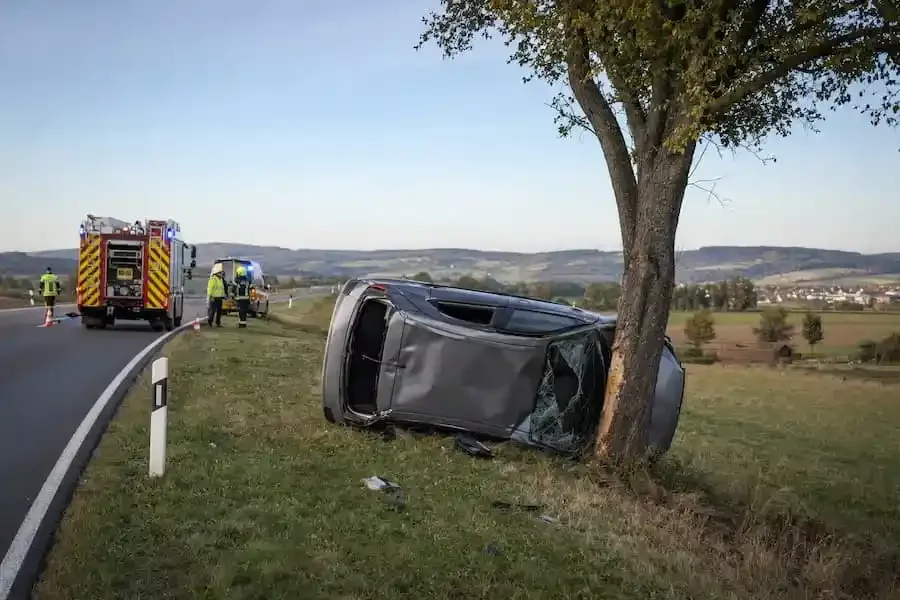 Grauer Kleinwagen liegt nach einem Verkehrsunfall bei Elfershausen seitlich an einem Baum