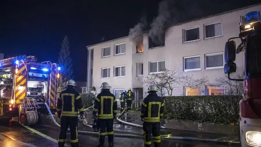 Feuerwehr bei einem nächtlichen Wohnungsbrand in einem Mehrfamilienhaus