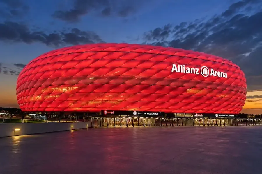 Die rot beleuchtete Allianz Arena in München, Austragungsort des Champions-League-Finales 2028.