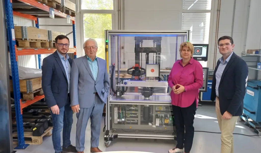 Unternehmensbesuch bei der ANT GmbH in Schweinfurt: Markus Holle, Hans Szczecina, Dr. Anna Barbara Keck und Viktor Ortel vor einer technischen Prüfanlage.