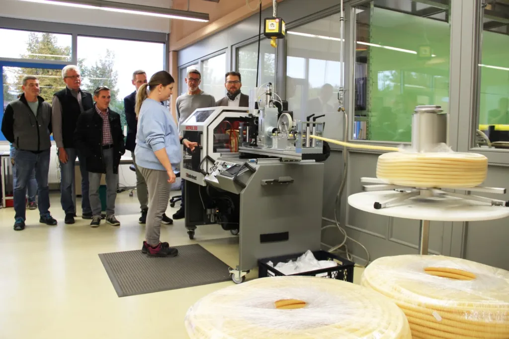 Jenny Schmitt demonstriert in der Lebenshilfe-Werkstatt Sennfeld einen neuen Wickelhalbautomaten zur Verarbeitung flexibler Kunststoffrohre vor Vertretern von FRÄNKISCHE und der Lebenshilfe Schweinfurt.