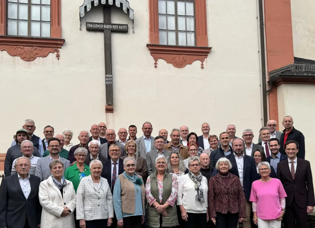 Gruppenfoto der ausgezeichneten Ehrenamtlichen aus dem Landkreis Schweinfurt vor der Alten Kirche in Schonungen mit Landrat Florian Töpper und seinen Stellvertretern.