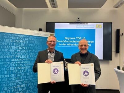 Preisverleihung im Staatsministerium in München mit zwei glücklichen Gesichtern (li. stellv. Leiter der Pflegeschule, Manfred Vogt; re. Leiter der Pflegeschule, Elmar Pfister)