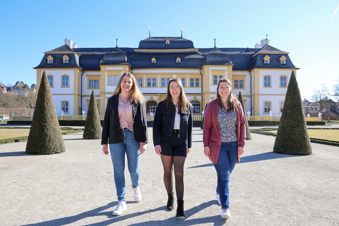 Königlicher Hintergrund für die beiden Aspirantinnen für das Amt der 67. Fränkischen Weinkönigin: Antonia Kraiß aus Nordheim am Main (links) und Vanessa Nüßlein aus Theilheim (rechts) und die amtierende 66. Fränkische Weinkönigin Lisa Lehritter in der Mitte vor dem Schloss Veitshöchheim, der ehemaligen Sommerresidenz der Fürstbischöfe von Würzburg und später der Könige von Bayern. Foto: Rudi Merkl / Gebietsweinwerbung Frankenwein-Frankenland GmbH
