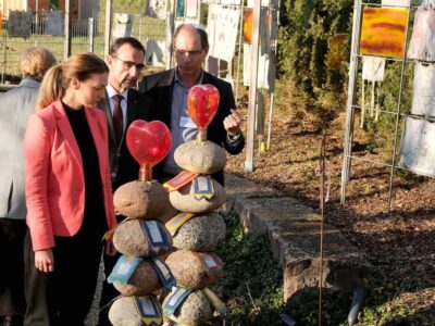 Alfons Regler, Geschäftsführung St. Nikolaus-süddeutsches Kinderhospiz gGmbH, erklärt Bayerns Gesundheits- und Pflegeministerin Judith Gerlach bei ihrem Besuch im Kinderhospiz St. Nikolaus in Bad Grönenbach die Bedeutung des „Fahnengartens“, wo von den Familien bei ihren Besuchen selbstgenähte Fahnen nach dem Tod des erkrankten Kindes aufgehängt werden. V.l.: Judith Gerlach, MdL Klaus Holetschek, Alfons Regler. Fotos: Brigitte Waltl-Jensen